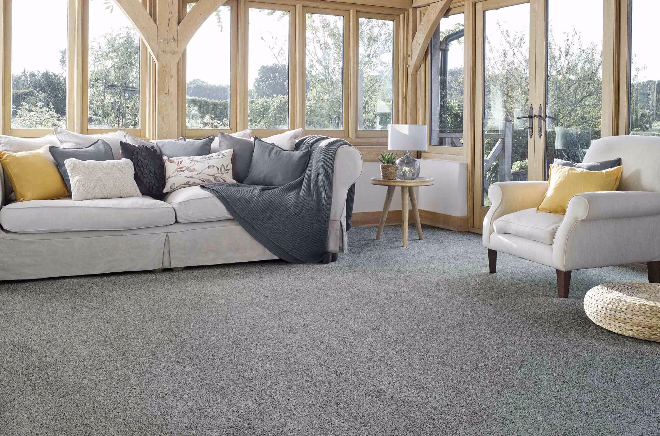 Grey carpet in a timber-framed living room with sofas and garden windows