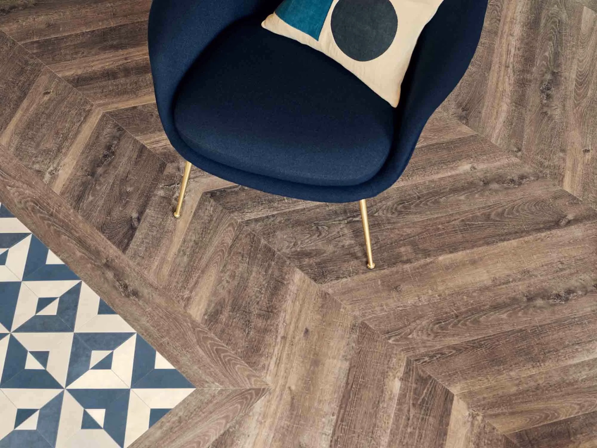 Grey wood-effect herringbone LVT flooring beside a navy armchair