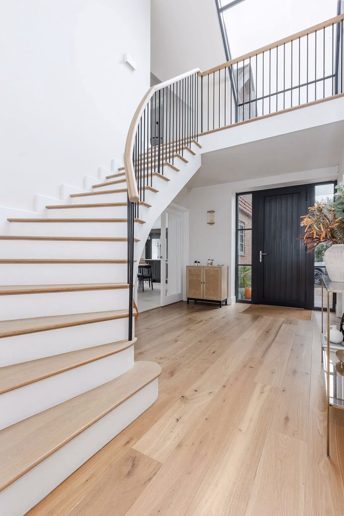 Engineered oak flooring in a bright hallway with a curved staircase